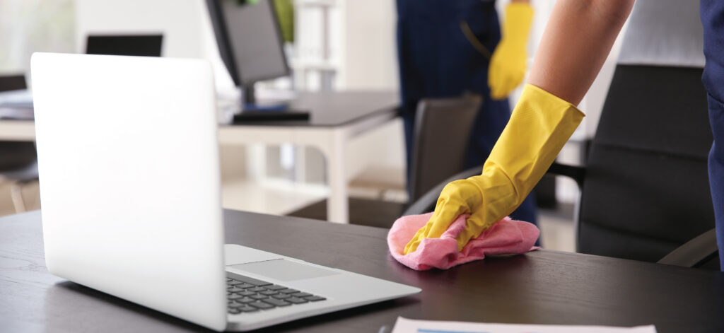 Wiping Off An Office Desk With A Cleaning Rag